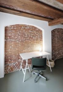 a white table and chair in front of a brick wall at CHARMANTES APARTMENT im Herzen von Linz in Linz