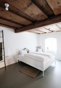 a white bedroom with a large white bed with wooden ceilings at CHARMANTES APARTMENT im Herzen von Linz in Linz