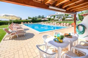 a patio with tables and chairs and a swimming pool at Apartamentos Flor da Laranja, Albufeira in Albufeira