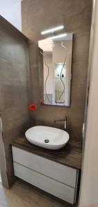 een badkamer met een witte wastafel en een spiegel bij La Casa di Anna in Gargnano