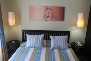 a bedroom with a bed with two blue and white pillows at Hotel Ordem De Santiago in Alcácer do Sal