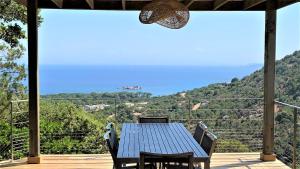 a blue table and chairs on a deck with a view at A ALTEZZA Palombaggia in Porto-Vecchio