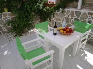 uma mesa branca com uma taça de fruta e uma garrafa de vinho em Nicolas Antiparos em Antiparos Town