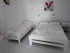 two white beds in a room with two tables at Nicolas Antiparos in Antiparos