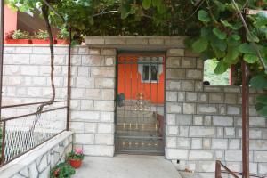 pomarańczowe drzwi na murze z klatką schodową w obiekcie Apartman Vlačić w mieście Trebinje