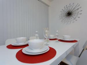 a white table with red and white plates and wine glasses at Shaftesbury Apartment in Leeds