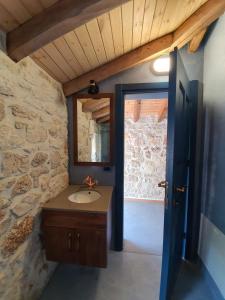een badkamer met een wastafel en een stenen muur bij Roots Dhermi in Dhërmi