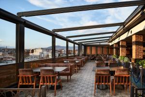 a restaurant with tables and chairs on a balcony at Hotel Gold in Skopje