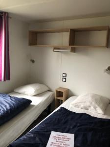 twee bedden in een kleine kamer met een bord erop bij Camping du Sevron in Saint-Étienne-du-Bois