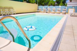 a swimming pool with chairs and a pool noodle in the water at Hotel Diplomatic - Bianchi Hotels in Cesenatico