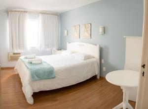 Un dormitorio con una gran cama blanca y una mesa en Hotel Domo, en Prudentópolis