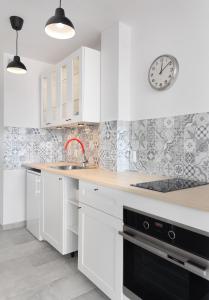 a kitchen with white cabinets and a clock on the wall at Bagno Cozy Studio II in Warsaw