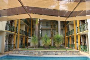 an apartment building with a swimming pool and palm trees at Hotel Cascada Huasteca in Tanchachín