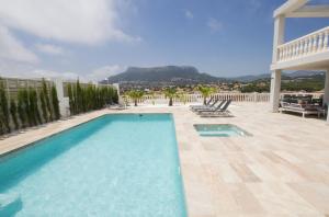 a swimming pool with chairs on a patio at Villas Guzman - Grandiosa in Calpe