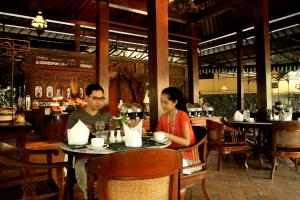 a man and woman sitting at a table in a restaurant at Laras Asri Resort & Spa in Salatiga