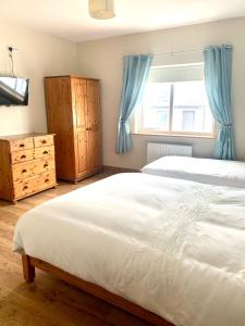 a bedroom with a large white bed and a window at Wild Atlantic Way Cottage in Achill