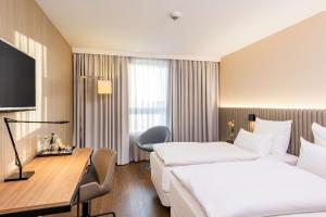 a hotel room with two beds and a desk at NH Hamburg Altona in Hamburg