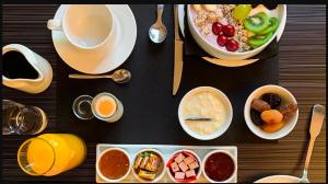 - une table avec des bols de nourriture et une tasse de café dans l'établissement Hôtel-Spa-Piscine Le Petit Castel Beuzeville-Honfleur, à Beuzeville