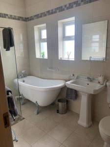 La salle de bains blanche est pourvue d'une baignoire et d'un lavabo. dans l'établissement Wild Atlantic Way Cottage, à Achill