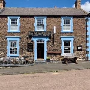 Un viejo edificio de ladrillo con ventanas azules y una puerta. en The Nook, en Embleton