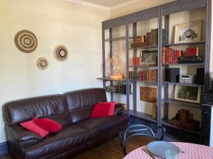 a living room with a brown leather couch and book shelves at Et au pied coule une rivière, situation et vue idéales in Auxerre