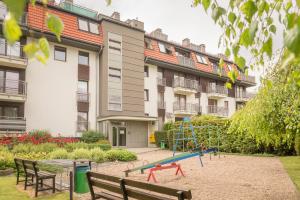 a playground in a park in front of a building at Apartamenty Polanica MyWeek in Polanica-Zdrój