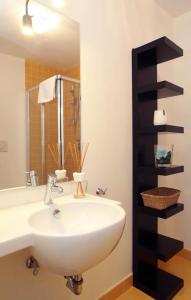 baño con lavabo blanco y estante negro en San Teodoro Apartment en Roma