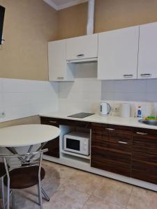 a kitchen with white cabinets and a table and a microwave at ACAPULCO in Pivdenne