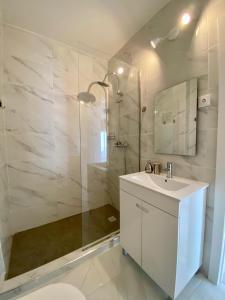 een witte badkamer met een wastafel en een douche bij White Sand Apartments Downtown Albufeira in Albufeira