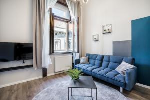 a living room with a blue couch and a tv at K33- Quality Apartments, Best Location, by BQA in Budapest