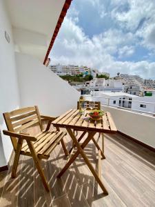 a wooden table and chair on a balcony with a view at White Sand Apartments Downtown Albufeira in Albufeira