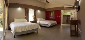 a bedroom with two beds and a red wall at Guácima Escondida Hotel Boutique in Guácima