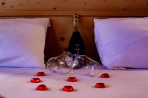una bottiglia di vino e rose rosse su un letto di Albergo Centrale a Canazei