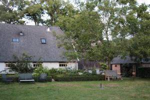 une maison avec un banc et des chaises dans la cour dans l'établissement Hoeve Op Vollenhof, à Wezep