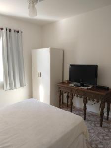 a bedroom with a bed and a desk with a television at Casa da Lili-ESPAÇO INDEPENDENTE E PRIVATIVO in Brotas