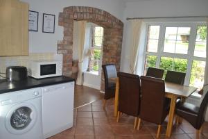 una cucina e una sala da pranzo con tavolo e forno a microonde di Sally Gardens Cottage a Downpatrick