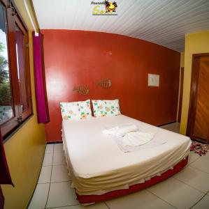 a bed in a room with a red wall at Pousada Sena in Flecheiras