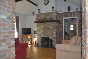 un soggiorno con camino in pietra con divano e poltrona di Sally Gardens Cottage a Downpatrick