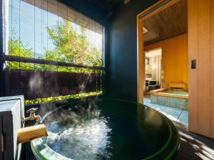 uma banheira na casa de banho com uma janela em Yufuin Bettei Itsuki em Yufu