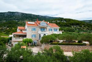 een groot huis met blauwe ramen op een heuvel bij Villa Franka with pool in Bol