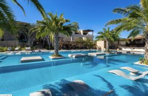 a swimming pool with lounge chairs and palm trees at Bohari Palmilla in San José del Cabo