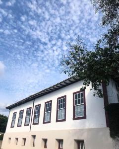 - un bâtiment blanc avec des fenêtres et un ciel nuageux dans l'établissement Pousada Travessia - Minas Gerais, à Três Pontas