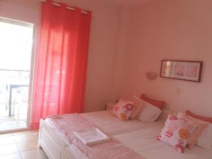 a bedroom with a bed with red curtains and a window at By the Sea Apartments-studios in Siviri