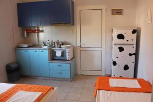 cocina con armarios azules y nevera blanca en By the Sea Apartments-studios, en Siviri