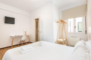a white bedroom with a white bed and a desk at Hostal Jume - Urban Rooms in Mahón