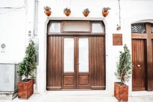 a wooden door on a building with two potted plants at Civico 5 in Alberobello