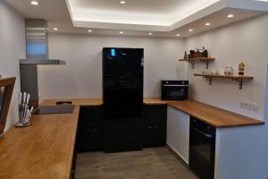 a kitchen with a black refrigerator and wooden counter tops at Maison du Troubadour in Balazuc