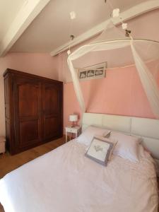 Schlafzimmer mit einem weißen Bett und einem Holzschrank in der Unterkunft B&B Le Patio En Ville - Chambres d'hôtes in Narbonne