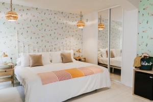 1 dormitorio con cama blanca y papel pintado con motivos florales en Hotel Mar Azul & Surf, en Suances