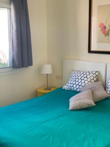 a bedroom with a green bed with a window at Ático Romano in Estepona